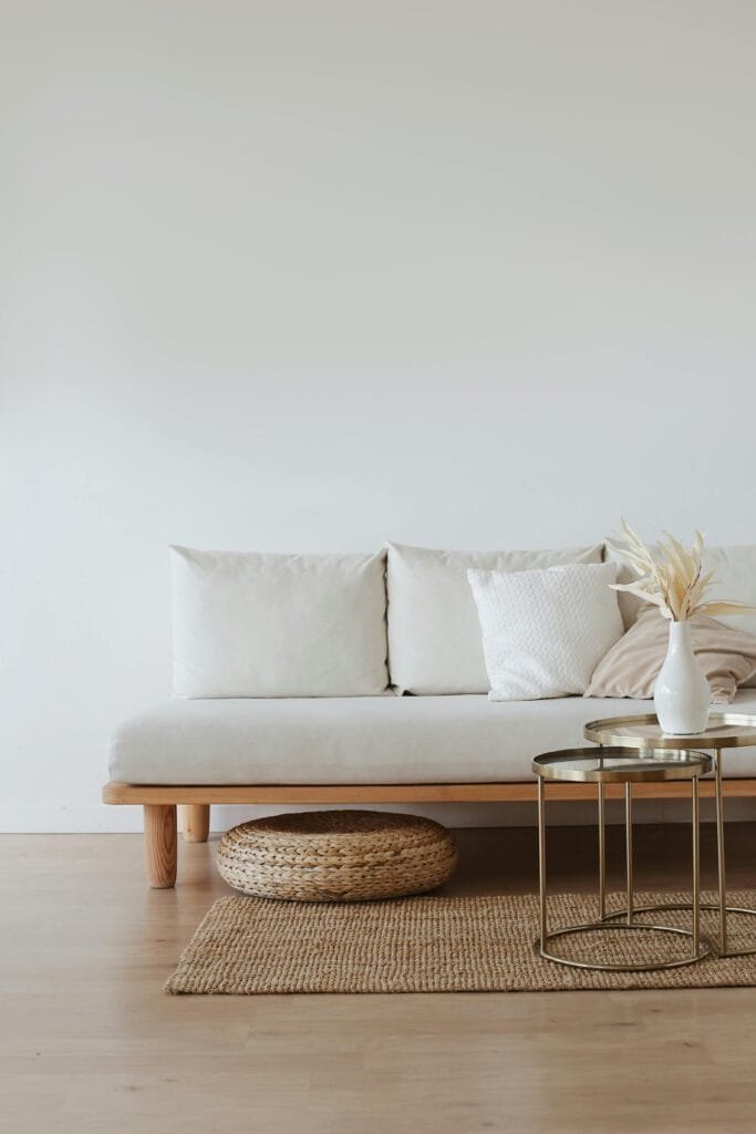 Home_picture-Furniture and mum A chic minimalist living room featuring a white sofa with cushions, dried flowers in a vase, and a wooden floor.